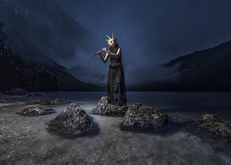 Musikerin auf einem Stein stehend bei Regen