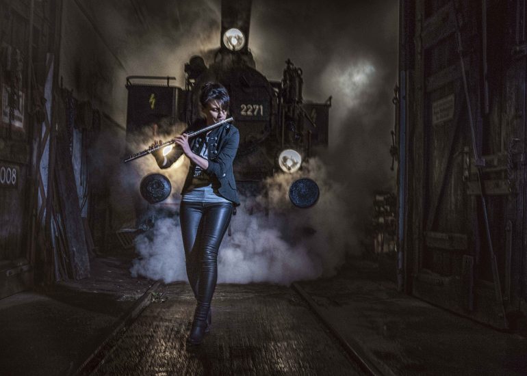 Eine Musikerin vor einer alten Dampflokomitive